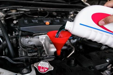 Pouring coolant fluid using a funnel into car radiator Foto stock