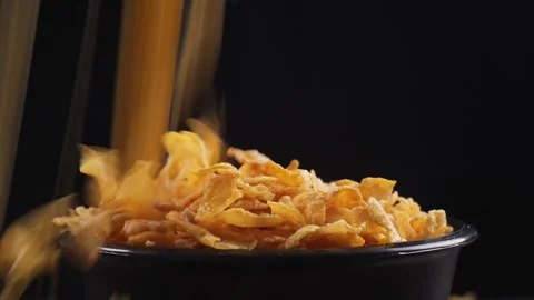Pouring corn flakes into empty bowl isolated black background Stock Footage 279700515