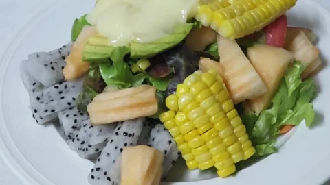 Pouring creamy dressing over fresh fruit and vegetable salad. Stock Footage 345292737