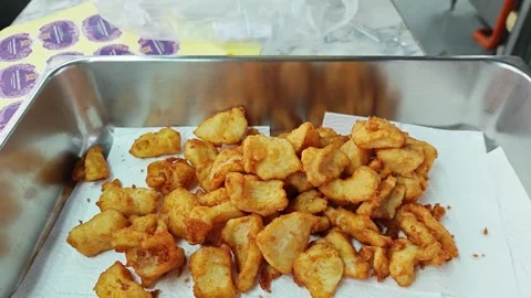 Pouring crispy fried fish from a colander onto paper towels. Видео 342740307