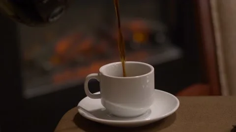 Pouring cup of coffee in front of the fire Stock Footage 142178706