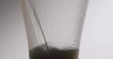 Pouring dark stout beer in a chilled glass on a white background Stock Footage 342736103