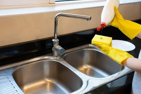 Pouring Dish Soap onto Sponge at Kitchen Sink Stock Photos
