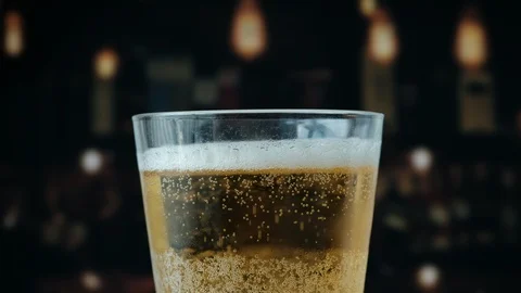 Pouring a draught lager beer from the top glass forming waves Stock Footage 87196151