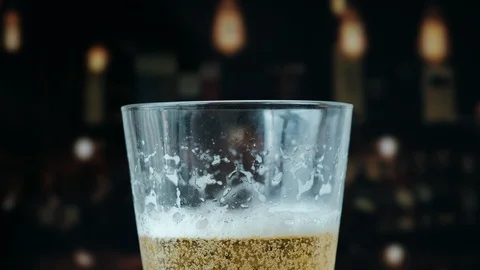 Pouring a draught lager beer from the top glass forming waves Stock Footage 87196204