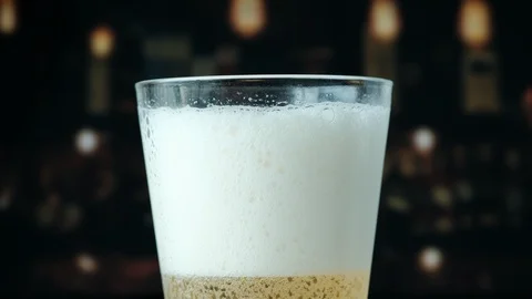 Pouring a draught lager beer from the top glass forming waves Stock Footage 87196300