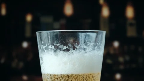 Pouring a draught lager beer from the top glass forming waves Stock Footage 87196317