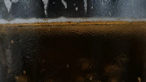 Pouring a draught lager beer from the top glass forming waves Stock Footage 87196761