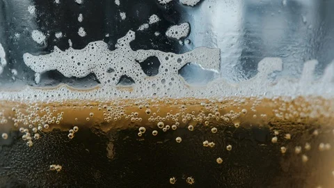Pouring a draught lager beer from the top glass forming waves Stock Footage 87196852