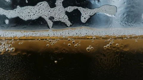 Pouring a draught lager beer from the top glass forming waves Stock Footage 87197123