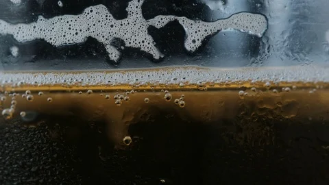 Pouring a draught lager beer from the top glass forming waves Stock Footage 87197141