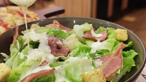 Pouring dressing on fresh Caesar salad. Видео 340201417