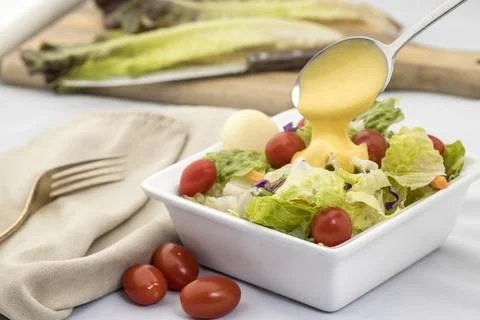 Pouring dressing on a salad. Stock Photos