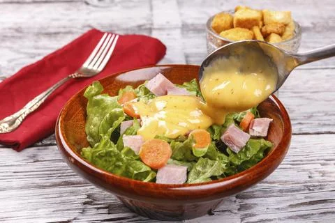 Pouring dressing on a salad. Stock Photos