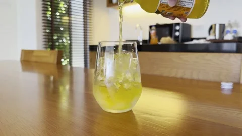 Pouring Drink Into Glass Ice Cubes Close Up  Indoor Table 4K HDR Editorial Stock Footage 335698142