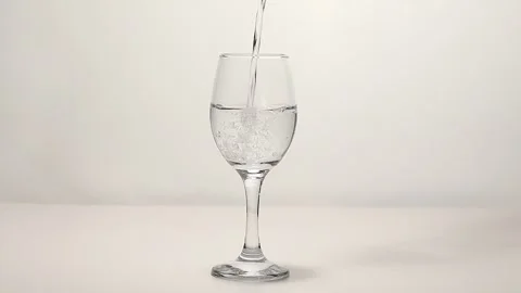 Pouring drinking water into a drinking glass placed on a turntable Stock Footage 249973490