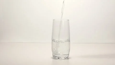 Pouring drinking water into a drinking glass placed on a turntable Stock Footage 249973494