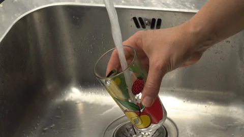 Pouring  drinking water from a kitchen tap into a glass. Stock Footage 108318103