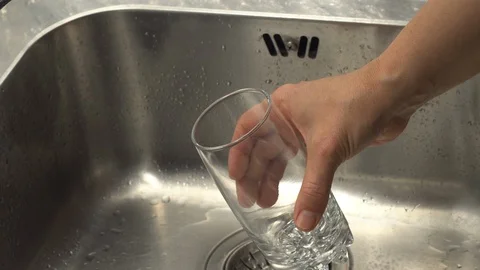 Pouring  drinking water from a kitchen tap into a glass. Video stock 108318169