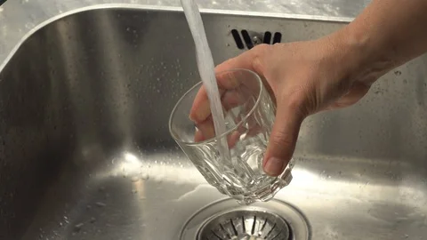 Pouring  drinking water from a kitchen tap into a glass. Video stock 108318181