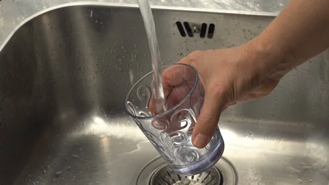 Pouring  drinking water from a kitchen tap into a glass. Video stock 108318629