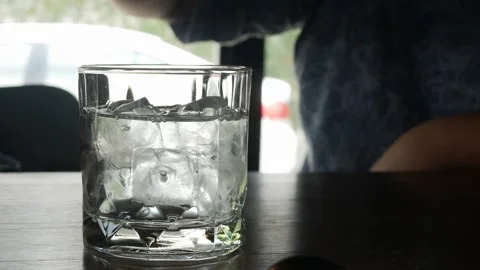 Pouring drinking water from plastic bottle over a glass of ice cubes for dr.. Stock Footage 284211007