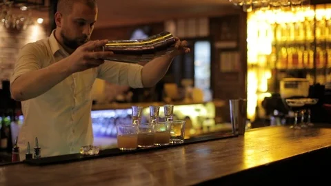 Pouring drinks into shots using multiple shaker Stock Footage 106183066