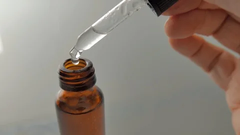 Pouring drops of liquid in an amber bottle with a dropper Stock Footage 101297049