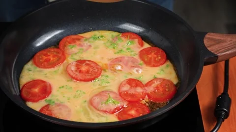 Pouring Egg and Parsley Mixture over Tomatoes in a Frying Pan Stock Footage 342278563