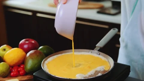 Pouring egg mixture into frying pan in indoor kitchen setting 库存影片 342830308