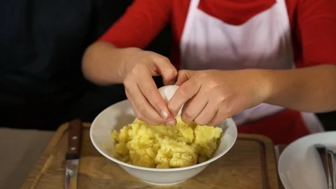 Pouring eggs into a pot of potatoes Stock Footage 123650987