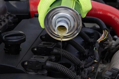 Pouring Engine Oil Into a Car Engine During Maintenance in a Garage on a Su.. 스톡 사진