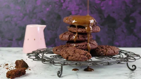 Pouring extra chocolate sauce over stack of chocolate chip homemade cookies. Stock Footage 132374418
