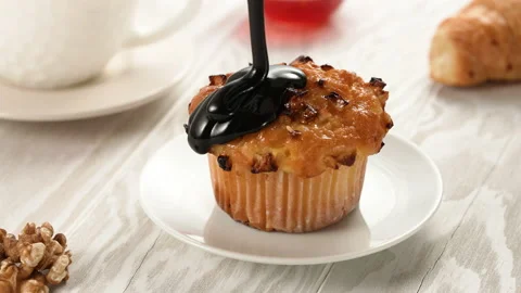 Pouring extra dark melted chocolate sauce or syrup on homemade muffin cake in Stock Footage 155511902