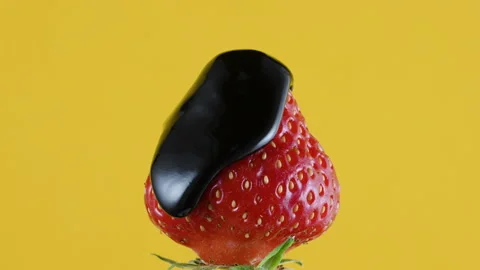 Pouring extra dark melted liquid chocolate sauce over fresh strawberry on yellow Stock Footage 155512317