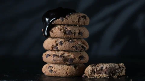 Pouring extra dark melted liquid chocolate sauce over stack of homemade cookies Stock Footage 155543352