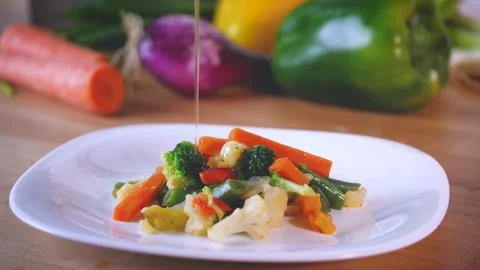Pouring extra virgin oil on cooked vegetable on white dish. Pieces of carrots, Stock Footage 144260267