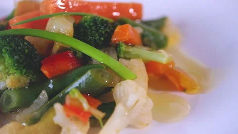Pouring extra virgin oil on cooked vegetable on white dish. Pieces of carrots, b Stock Footage 144260434