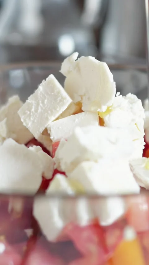 Pouring extra virgin olive oil over fresh feta cheese and chopped tomatoes in a Vídeo Stock 341283256