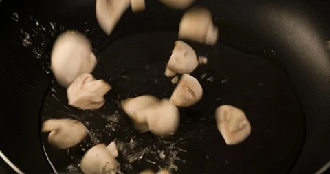 Pouring Falling champignons mushrooms in Pan with oil 4K Stock Footage 104060193