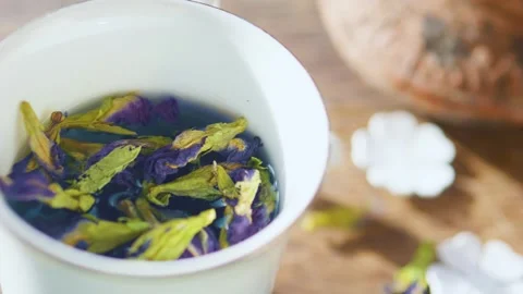 Pouring falling dried Blue Thai Anchan Butterfly pea flower tea into mug. Stock Footage 248229064
