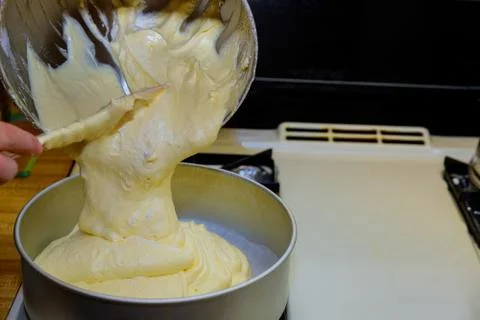 Pouring fluffy dough into round baking pan. Stock Photos