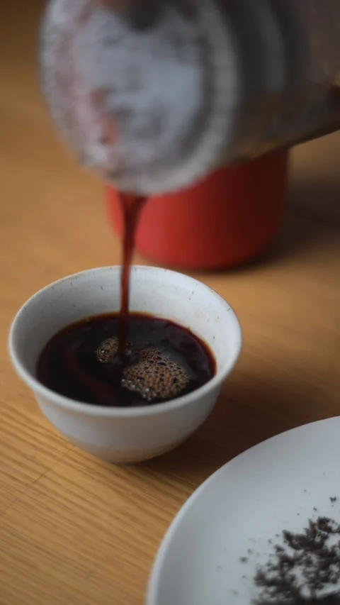 Pouring a fragrant chinese puer tea into a beautifully crafted traditional cup Stock Footage 303699341