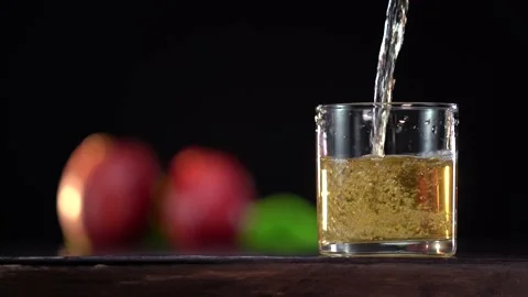 Pouring fresh apple juice into the glass on the dark background Stock Footage 154451453