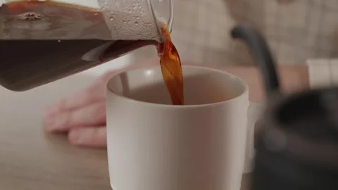 Pouring fresh black coffee into a ceramic cup close up Stock Footage 335143404