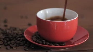 Pouring fresh coffee into red rotating cup Stock Footage 85806235