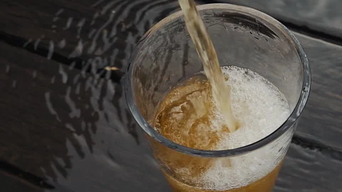 Pouring Fresh Craft Beer into Glass on Wet Dark Wood Table Stock Footage 342970153