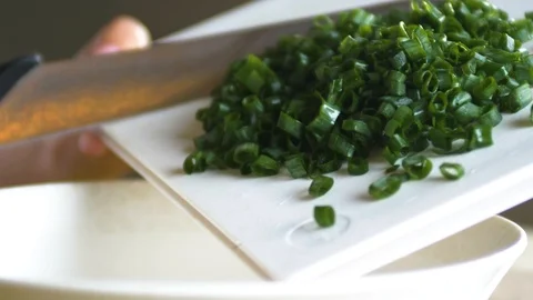 Pouring fresh green onion chives into a bowl with a big knife in slow motion Stock Footage