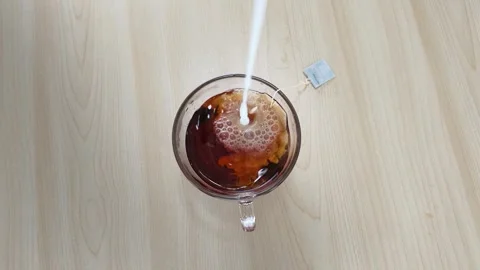 Pouring Fresh Milk into Brewed Black Tea Top Down View Stock Footage 346572415