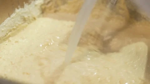 Pouring Fresh Milk into Flour Mixture for Homemade Dough Preparation Stock Footage 333600284